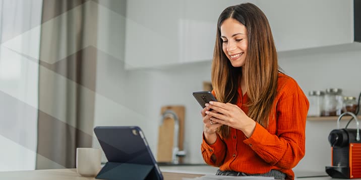 Une syndic bénévole consulte son téléphone à la table de la cuisine.